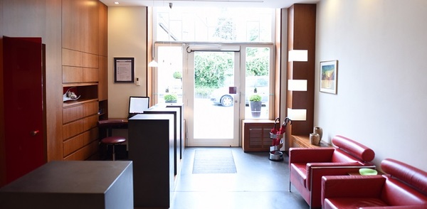 Heller Empfangsbereich einer modernen Praxis mit roten Ledersesseln und Schreibtisch.